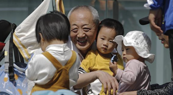 An elderly man plays with children in Beijing