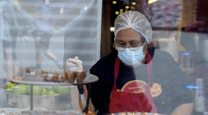 A worker wears a mask while preparing desserts at the Universal City Walk Friday, May 14, 2021, in Universal City, Calif.