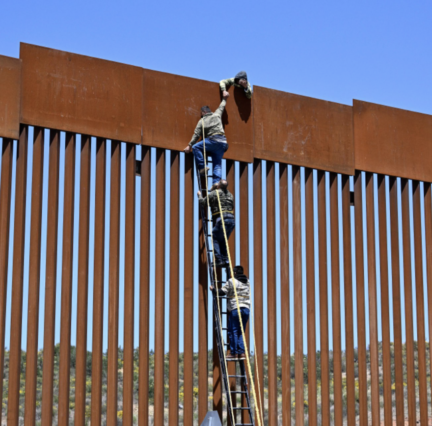 Immigrants attempting to climb border wall