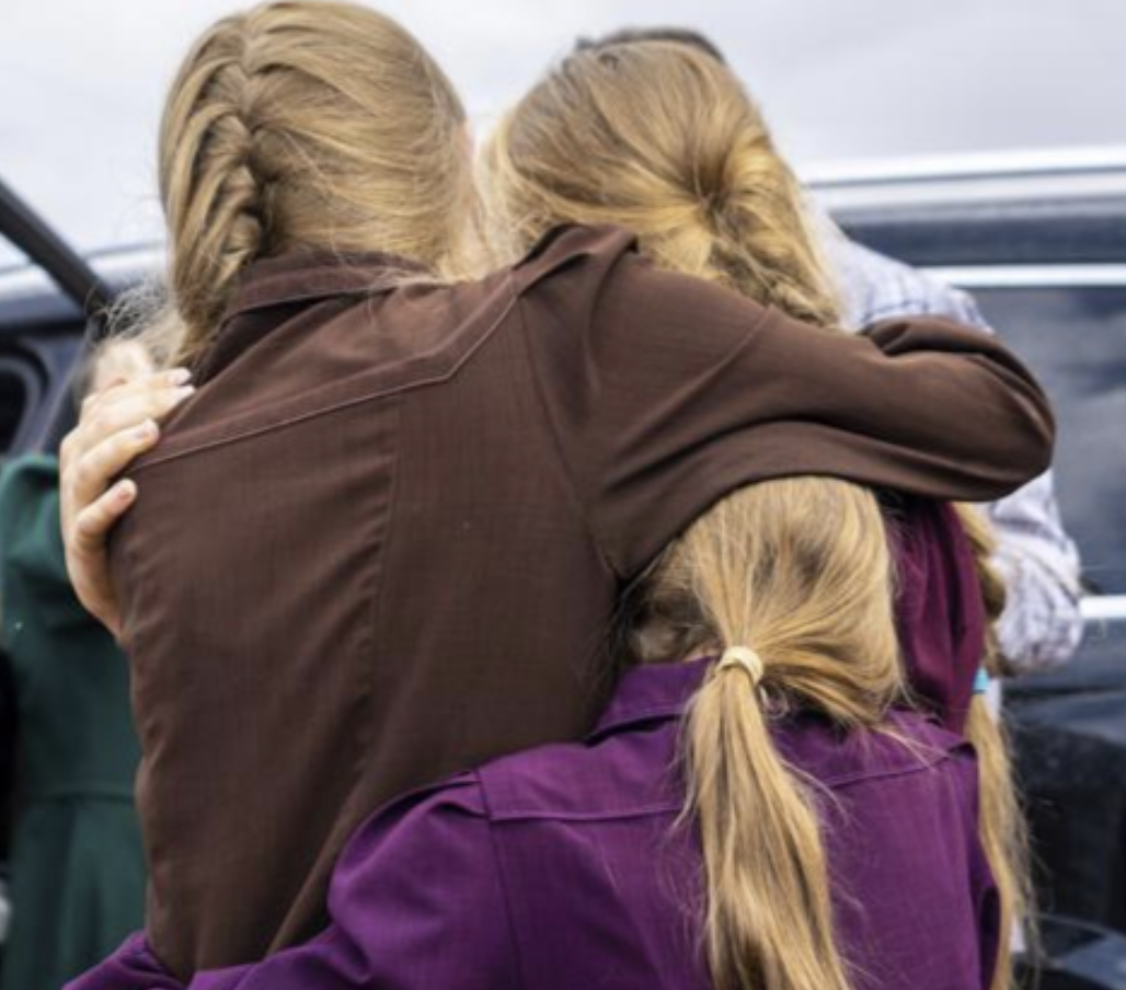Three girls embrace before they are removed from the home of Samuel Bateman,