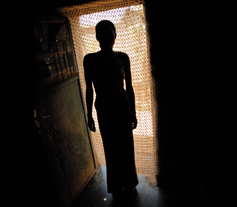 A women is seen in profile standing in a doorway