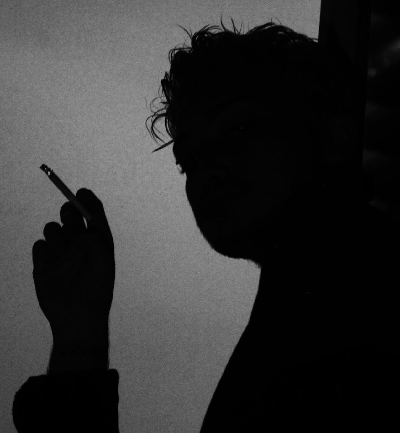 Silhouette of smoker with cigarette in darkness