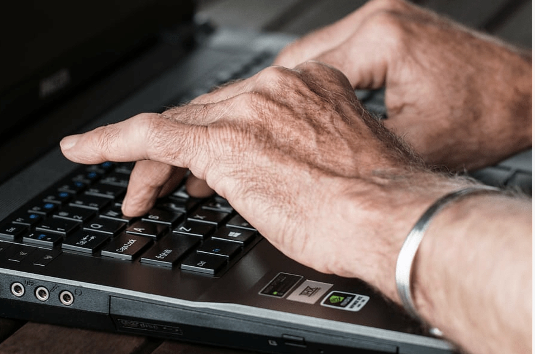 Hands of a senior typing on a computer