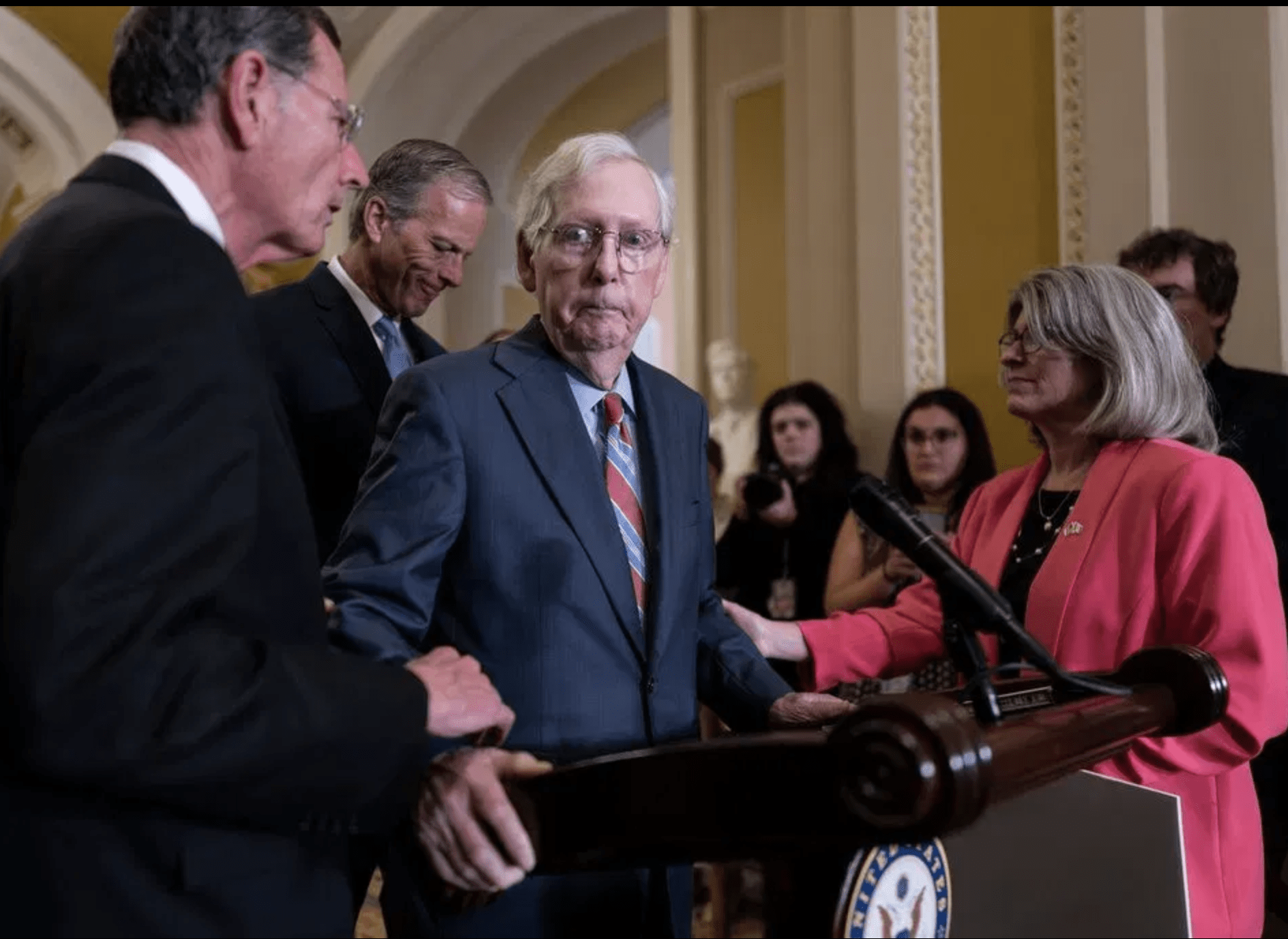 Senate Minority Leader Mitch McConnell, R-Ky., center, is helped by, from left, Sen. John Barrasso, R-Wyo., Sen. John Thune, R-S.D., and Sen. Joni Ernst, R-Iowa, after the 81-year-old GOP leader froze at the microphones as he arrived for a news conference, at the Capitol in Washington, Wednesday, July 26, 2023.
