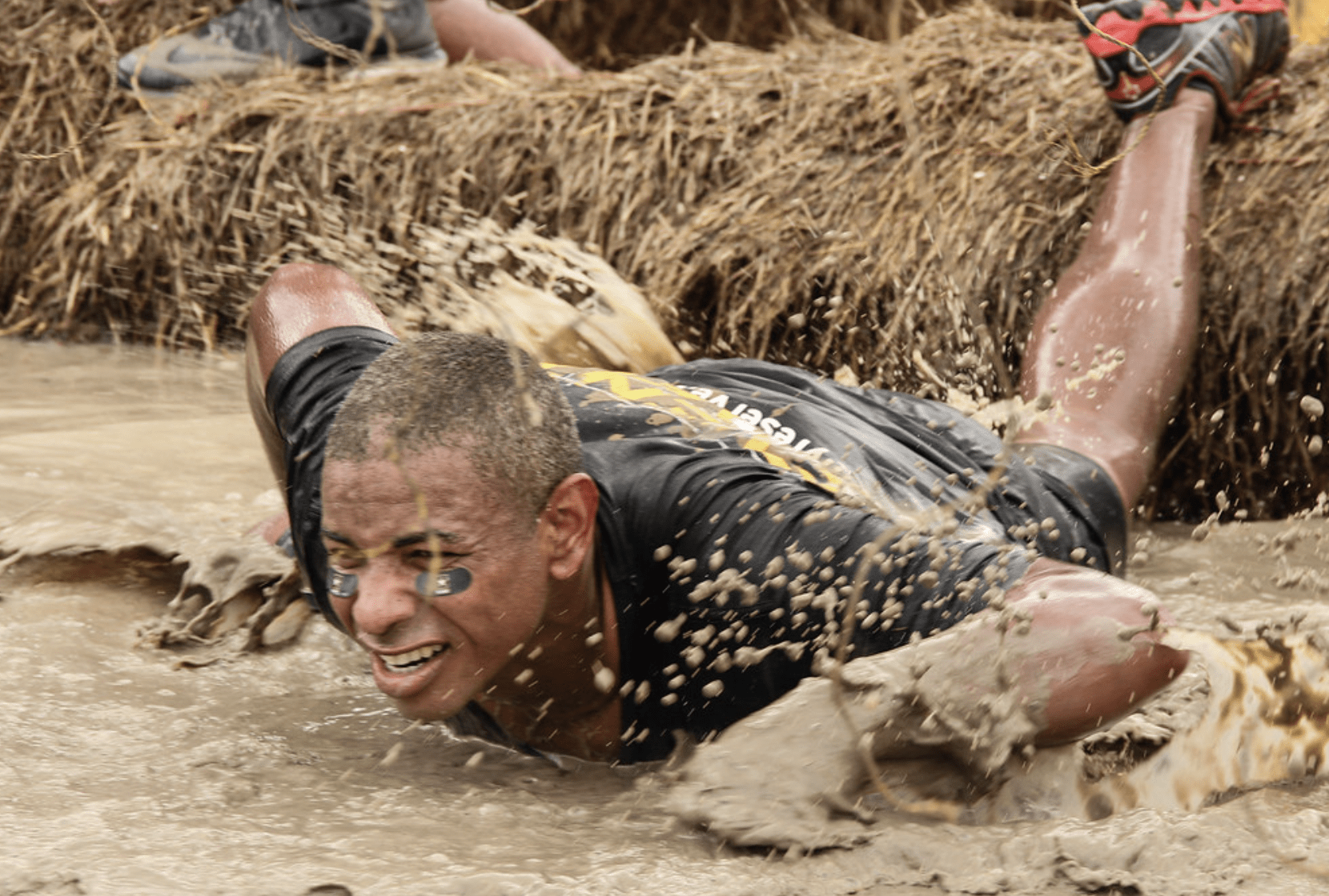 Game participant crawls through mud