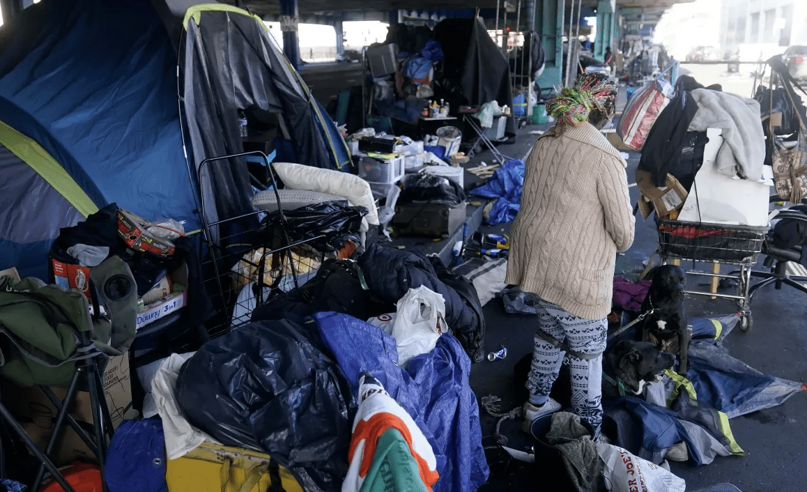 A woman gathers possessions to take before a homeless encampment was cleaned up in San Francisco, Tuesday, Aug. 29, 2023.