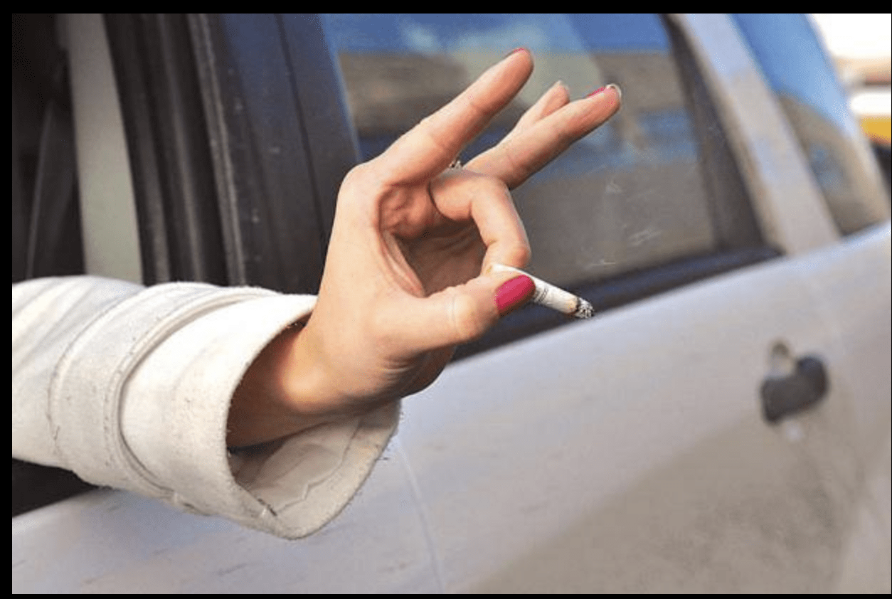 A person flicking a cigarette butt out a car. window