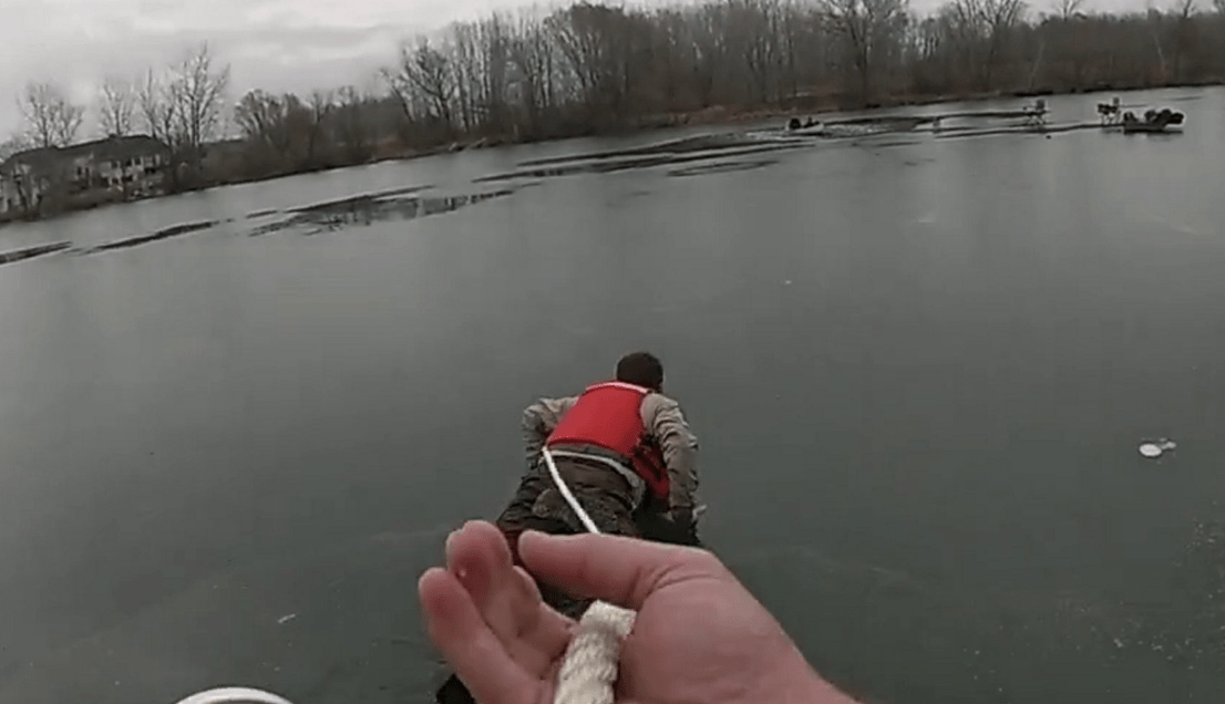 Deputy Chris Fjeld crawling across the ice to rescue two fishermen and a dog who had fallen through the ice. (Anoka County Sheriff's Office via SWNS)