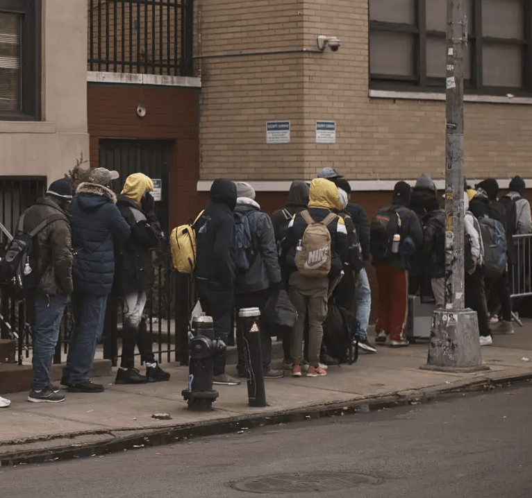 Migrants queue in the cold as they look for a shelter outside a migrant assistance center at St. Brigid Elementary School on Tuesday, Dec. 5, 2023, in New York. (AP Photo/Andres Kudacki)